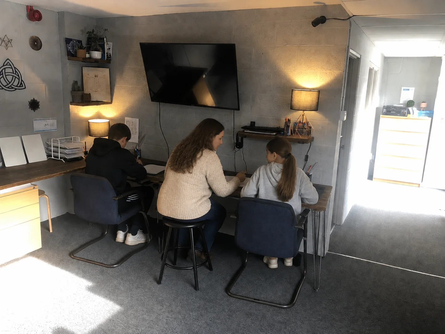 A tutor supporting two learners during a private tuition session